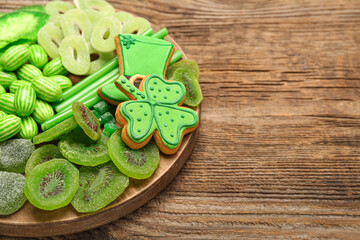 Board with different sweets for St. Patrick's Day celebration on wooden background, closeup