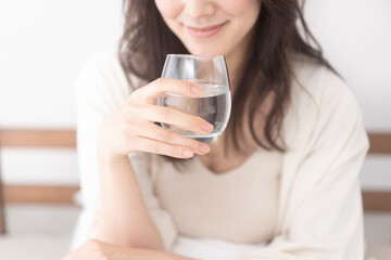 ベッドで水を飲む女性