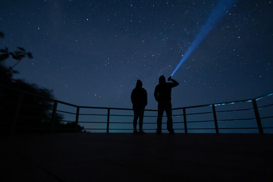 couple looking at the sky man holding a flashlight take looking at the night sky
