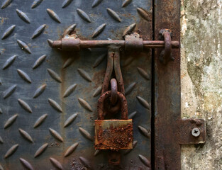 Rusty padlock hanging on the door of the trash can