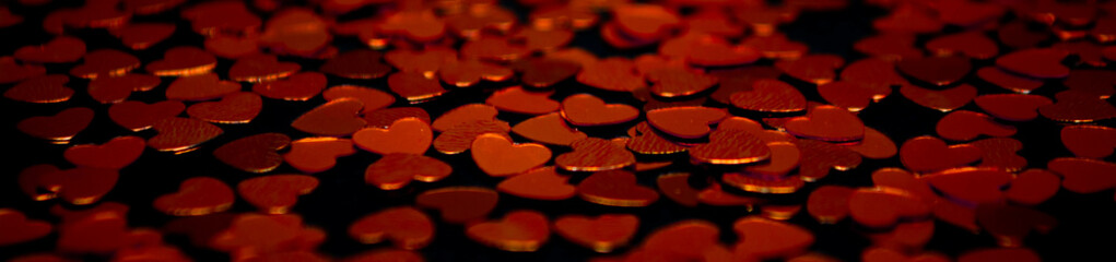 Banner of red festive confetti in the shape of a heart on a black background