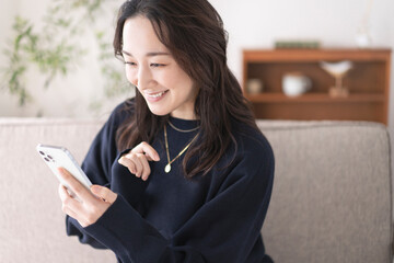 ソファーでスマホを持つ女性