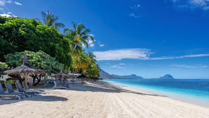 Paradise beach resort with palm trees and straw umbrellas and tropical sea in Mauritius island....