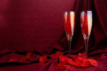 Valentines day background with champagne glasses and red ribbon on dark red background