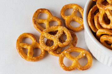 Salted pretzels in a white bowl close up. Option of serving snacks or crackers on a white background