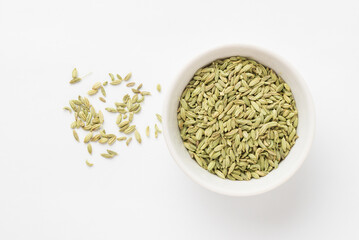 Top view of green aromatic fennel seeds in the ceramic bowl on white background. Fennel is ingredient of traditional Indian cuisine Ayurvedic nutrition