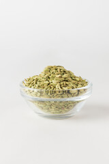 Green dry fennel seeds in the glass bowl on white background. Fennel is traditional Indian aromatic seasoning and ingredient of Ayurvedic cuisine