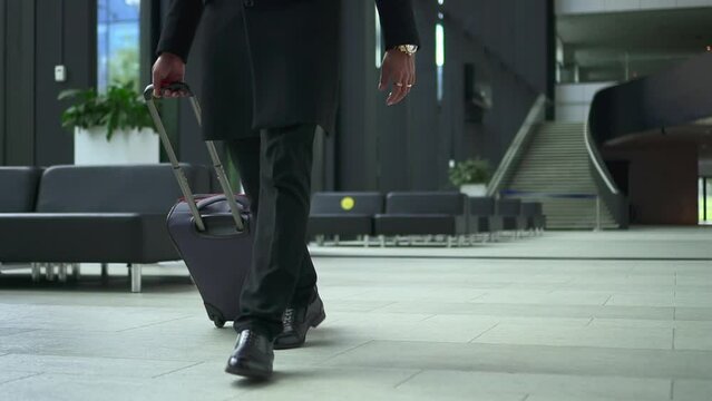 Closeup view of businessman or passenger walking with suitcase in hand in office or terminal spbd. Young male traveler moves luggage and walks in interior, waits for flight and heads to check-in