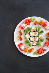 Traditional Japanese food - sushi, rolls on a white plate. Dark background. Top view
