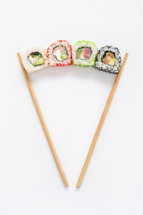Tasty sushi rolls with a chopstick on white background, top view