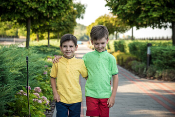 childhood, hiking, family, friendship and people concept - two happy kids walking along forest path