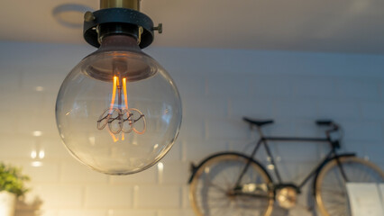Efficient incandescent light bulb waste electricity against a tiled wall with a small bike and a...