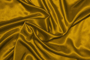 The texture of the satin fabric of mustard color, patterns of wrinkled lines, top view.
