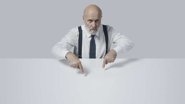 Confident businessman pointing at blank copy space