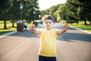 Happy child making a stop sign with his hand while standing at the road