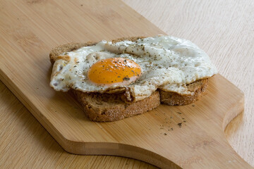 Slice of bread with baked egg on cutting board