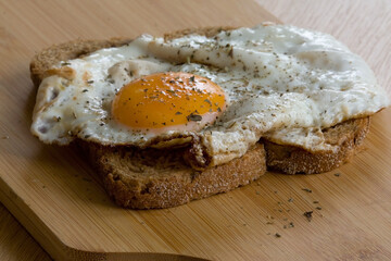 Slice of bread with baked egg on cutting board
