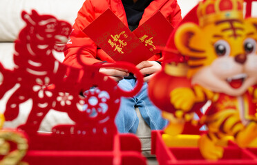 kid holding two red pockets with Tiger mascots in front the Chinese translation is everything goes well