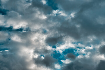 Dark dense cumulus clouds, deep textured & dramatic with a small tiny glimpse of blue sky.