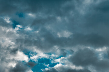 Dark dense cumulus clouds, deep textured & dramatic with a small tiny glimpse of blue sky.