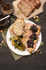 Sliced Traditional French terrine covered with bacon on dark wooden background