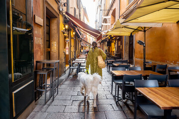 Famous gastronomical street with food stores and restaurants in Bologna city. Woman walking with her dog. Italian food and gastronomy concept © rh2010