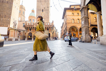 Stylish woman walks the street on background of famous towers in Bologna city. Italian lifestyle and street fashion concept. Idea of traveling Italy © rh2010