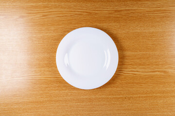 White round empty plate in the center of the table in beige color 