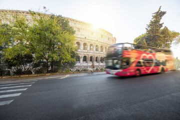 Street view with motion blurred tourist bus and Colosseum on background in Rome. Traveling Italian...