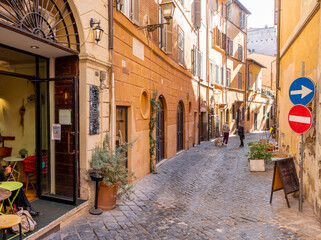 Fototapeta na wymiar Narrow street with cafe and small shops in Rome. Italy travel concept, visiting cozy places