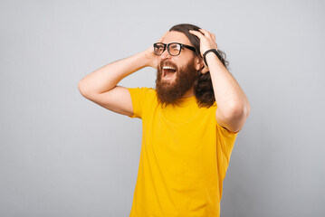 Excited young bearded man in yellow t-shirt screaming and celebrating.