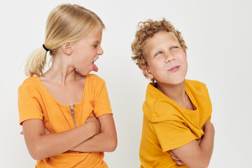 two joyful children in yellow t-shirts standing side by side childhood emotions light background unaltered