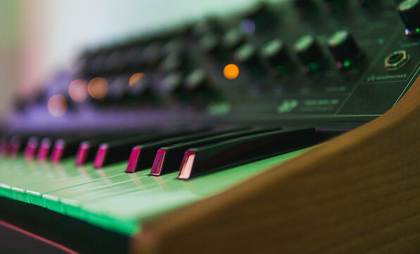 Close-up picture of the keyboard of a synthesizer with bokeh lights of its buttoms
