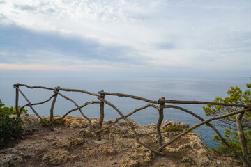 Cala Macarelleta, Menorca. September 2021. Paradise beach on the island of Menorca. Perfect place to relax and enjoy nature in summer. Wooden fence on the coastal path.