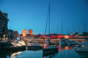 Oslo, Norway. Night View Embankment, Oslo City Hall And Moored Yachts Near Aker Brygge District. Summer Evening. Famous And Popular Place.Oslo, Norway. Night View Embankment, Oslo City Hall And Moored