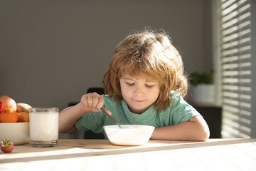 Portrait of cute child eating soup meal or breakfast having lunch by the table at home with spoon. Kids healthy food.