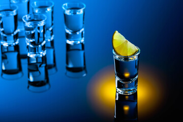 Tequila with lime slices on a black reflective background.