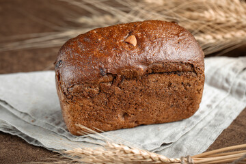 Fresh baked rye bread with dried fruits and nuts on brown background