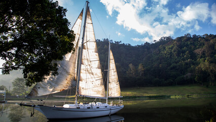 A beautiful white sailboat flaoting in nature lake