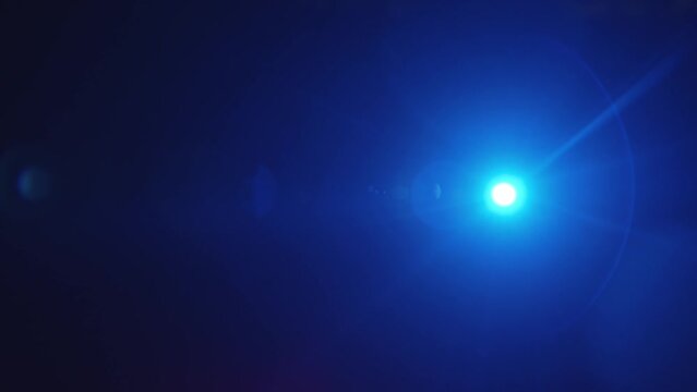 Long beam of blue spotlight in the dark with copy space and halo effect turns from side to side