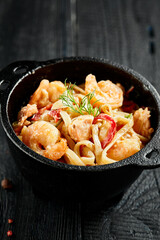 Stir fried udon noodles with shrimps in wok. Udon noodle with prawn on wooden background. Seafood...