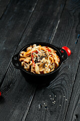 Stir fried udon noodles in wok. Udon noodle with chicken and mushrooms on wooden background. Asian...
