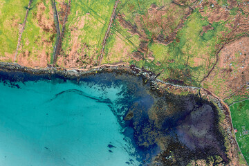Aerial top down view on green fields separated by stone fences and beautiful ocean surface. West...