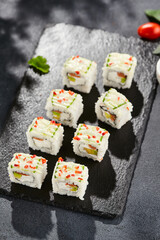 Fresh maki sushi on dark stone table. Colorful roll with vegetables. Sushi roll with salmon, avocado inside, cucumber outside. Style concept japanese menu with black background