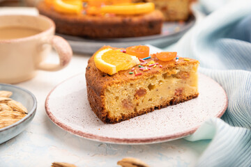 Orange cake with almonds and a cup of coffee on a white concrete background. Top view, selective focus.