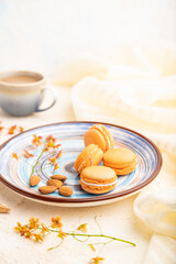 Orange macarons or macaroons cakes with cup of coffee on a white concrete background. Side view, selective focus.