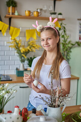 A young girl of 12 years old paints an egg for Easter