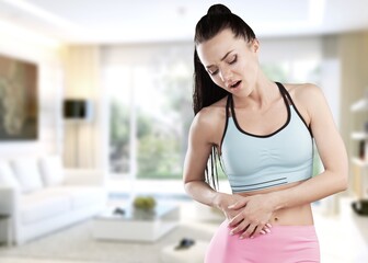 Young woman with arms on stomach and bending over with menstrual pain expression