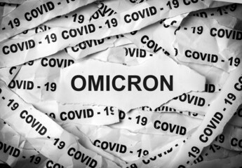 Several strips of paper printed with the words Covid-19 and Omicron. One of the strains of COVID-19.