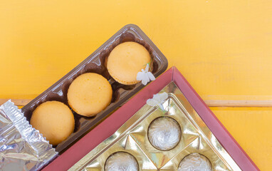 a box of macaroons with a box of chocolates on a yellow background